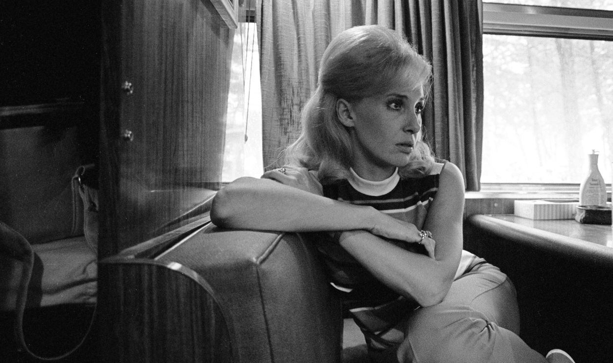 Country music performer and recording artist, Tammy Wynette sitting on her tour bus wearing a sleeveless striped shirt and Capri style pants. Shot full frame in Lavonia, Georgia 1971. Photo is part of the Nashville Music Collection.