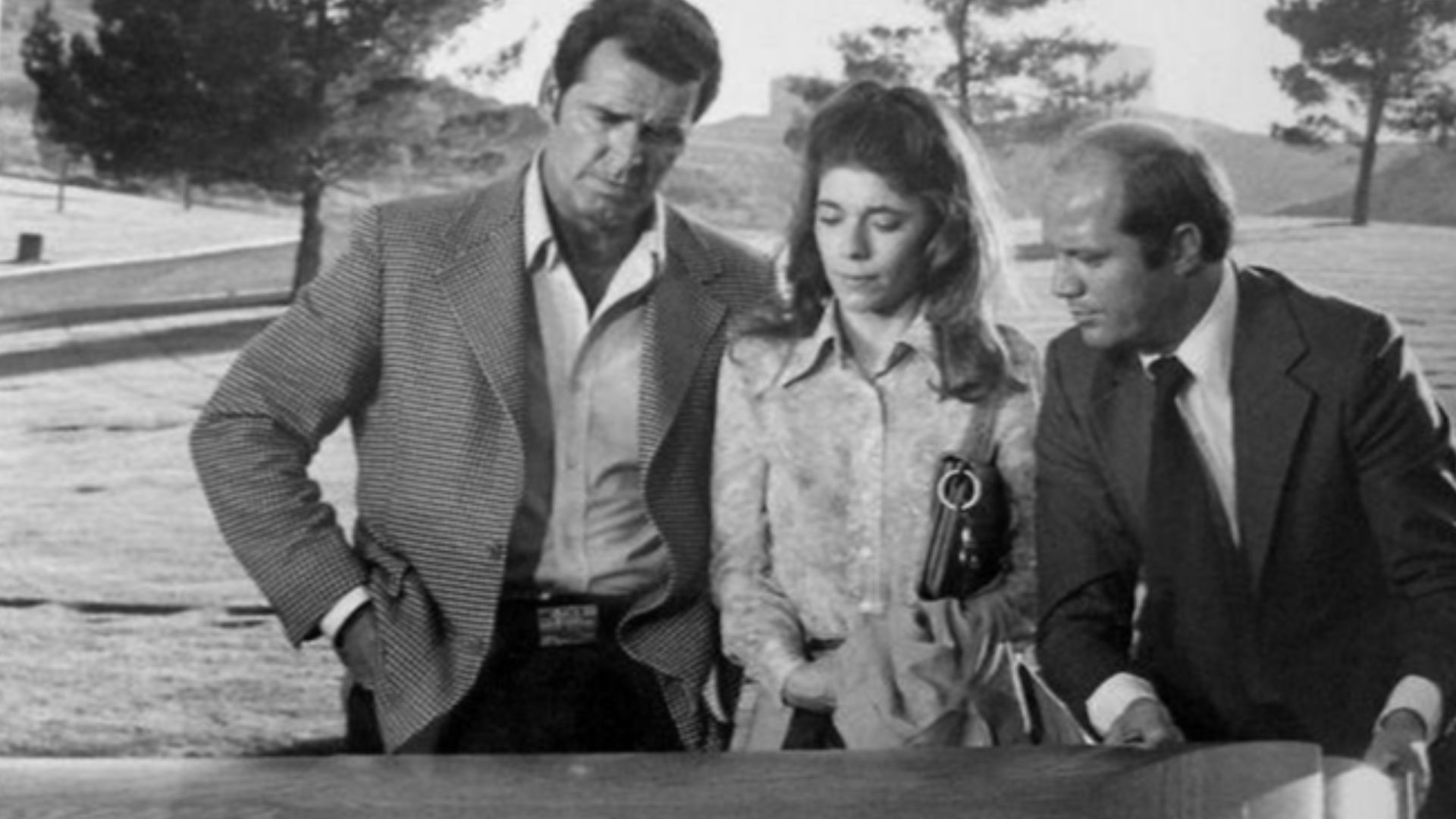Photo of James Garner as Jim Rockford, Sian Barbara Allen as a newspaperwoman and Dave Morick as the county coroner from the television program The Rockford Files.  In this episode,