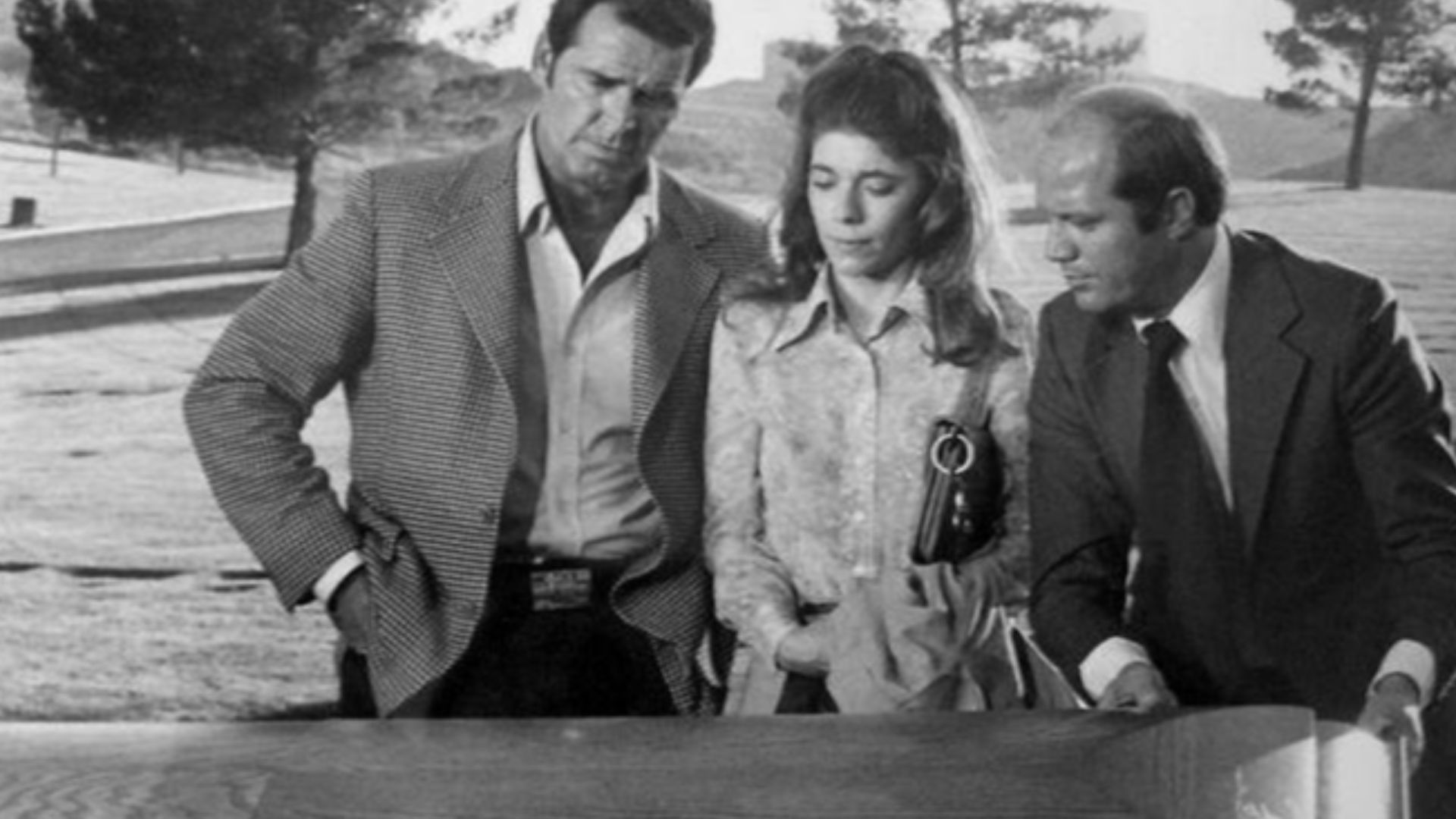 Photo of James Garner as Jim Rockford, Sian Barbara Allen as a newspaperwoman and Dave Morick as the county coroner from the television program The Rockford Files.  In this episode,