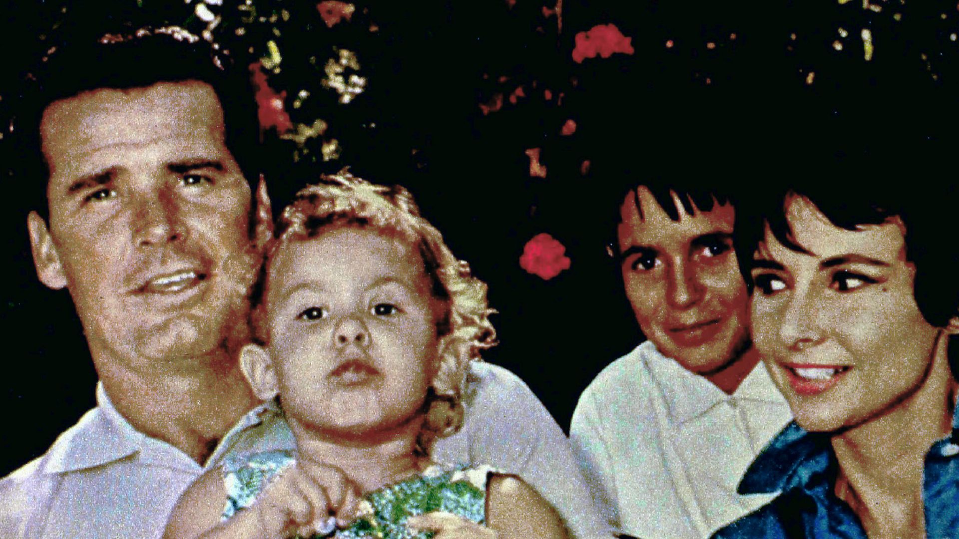 Photo of James Garner and his family.  Daughter Greta is on Garner's lap and daughter Kim is looking out between Garner and his wife, Lois.