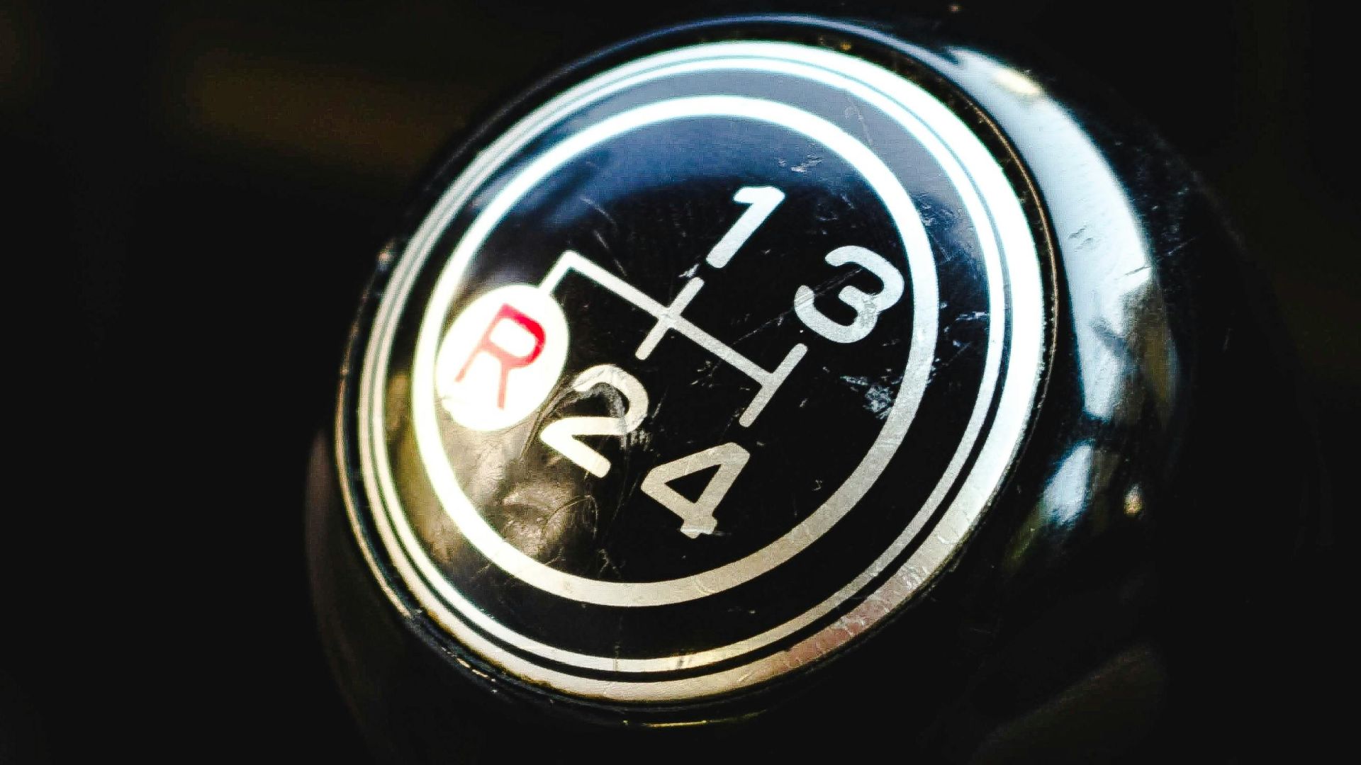Detailed view of a manual gear shift knob inside a vehicle, focusing on the gear pattern.