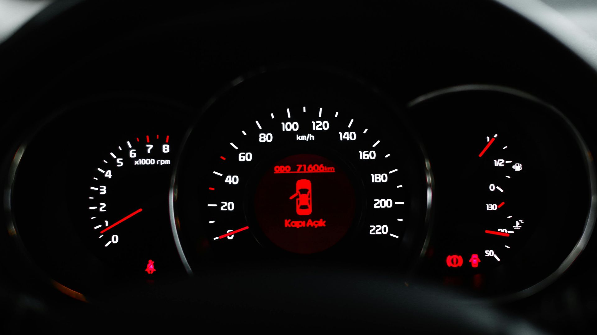 Car dashboard showing a warning light with various dials and gauges in focus.