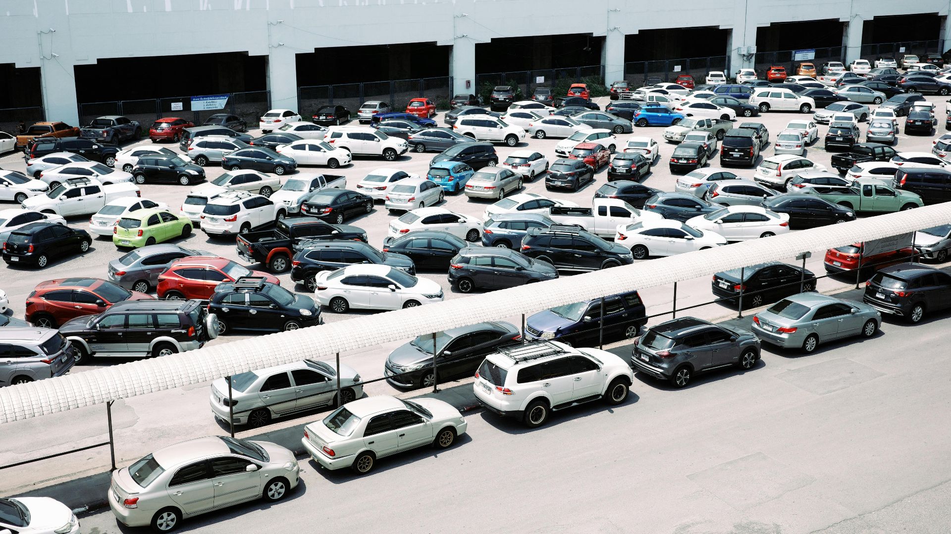High-angle view of a crowded urban parking lot filled with various parked cars.
