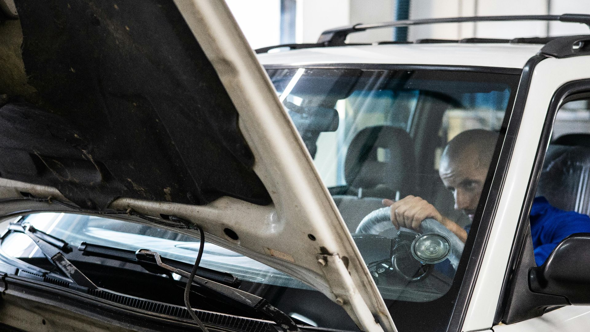 A mechanic performs a detailed inspection on a vehicle in a workshop setting.