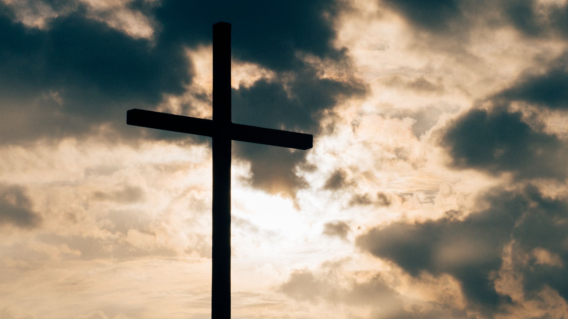 A cross at sunrise with clouds in the background