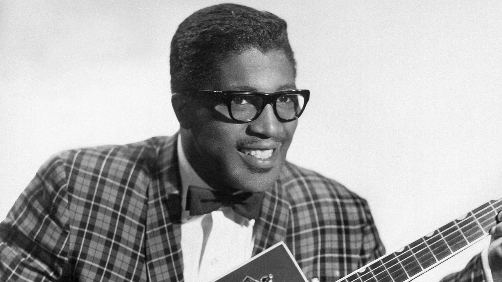 Publicity portrait of American blues musician Bo Diddley, 1957, sitting with his