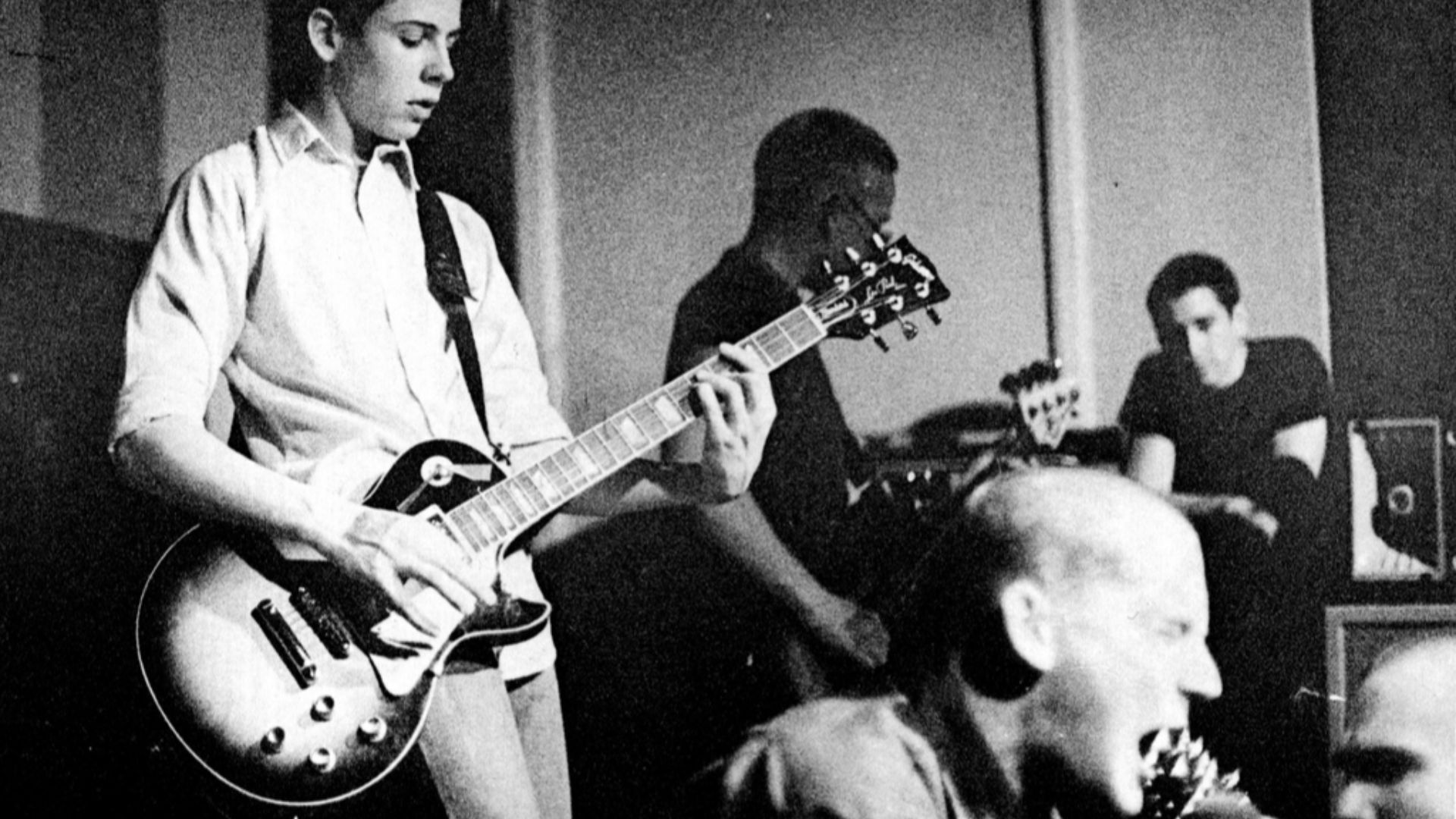 Minor Threat at The Wilson Center in Washington, D.C. 4/4/1981. Band members left to right: Lyle Preslar, Brian Baker, Ian MacKaye. Audience members: Mitch Parker in the background, Henry Rollins on the lower right.