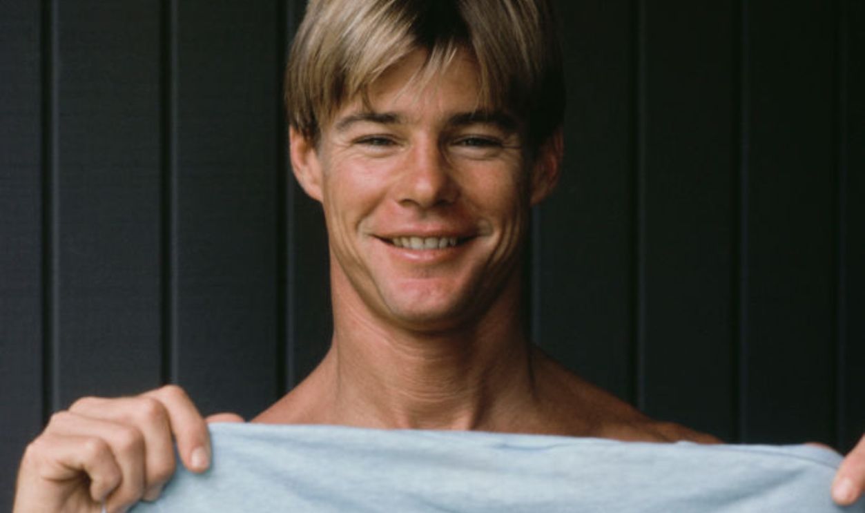 American actor Jan-Michael Vincent holding up a 'Pipeline Masters Hawaii 1977' t-shirt during the filming of 'Big Wednesday', at Sunset Beach, on the north shore of Oahu (Oʻahu), Hawaii, September 1977. Directed by John Milius, the American coming-of-age surfing drama starred Vincent as Matt.
