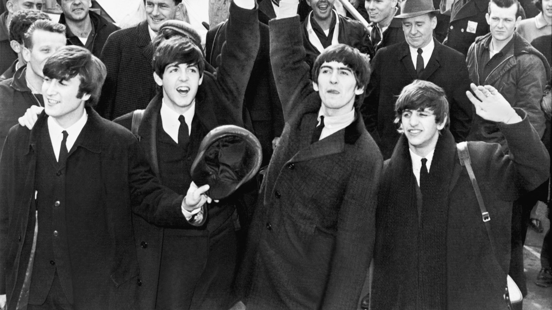 English band The Beatles wave to fans after arriving at Kennedy Airport.