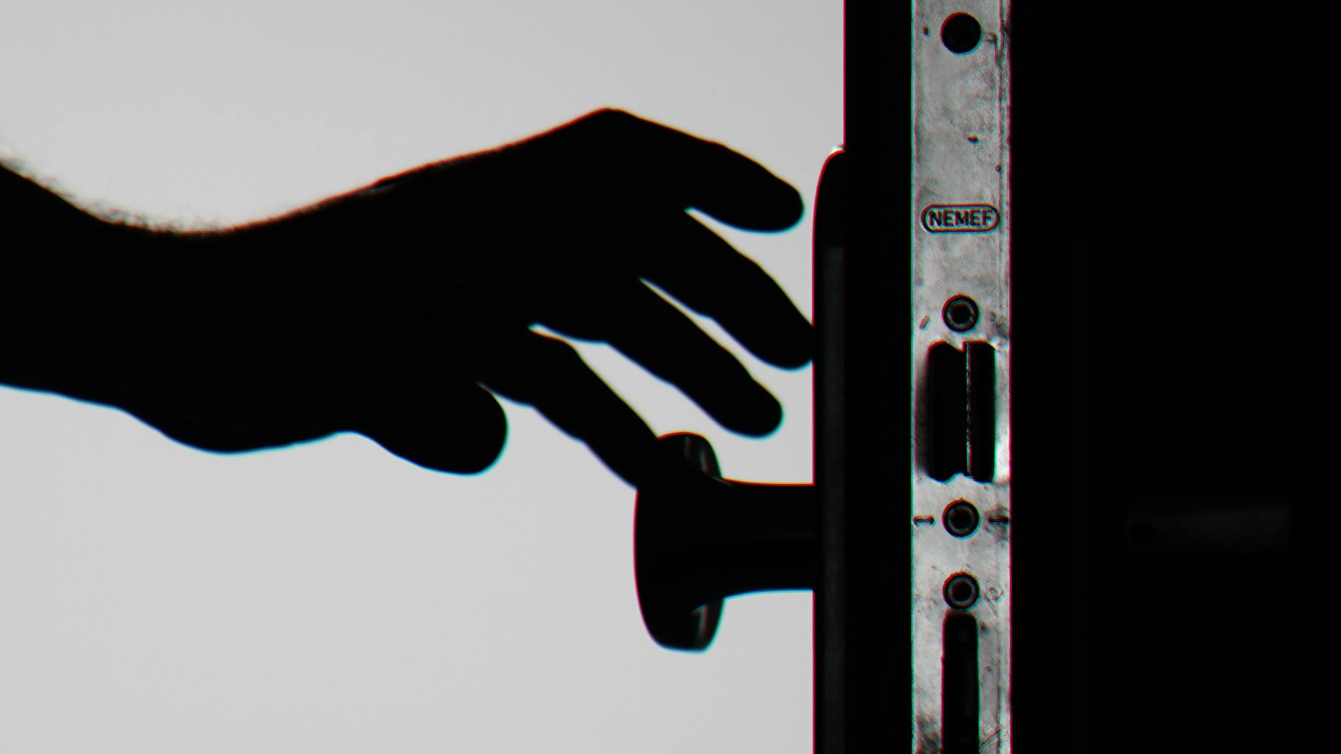 Silhouette of a hand about to open a door with keys in lock, symbolizing security.