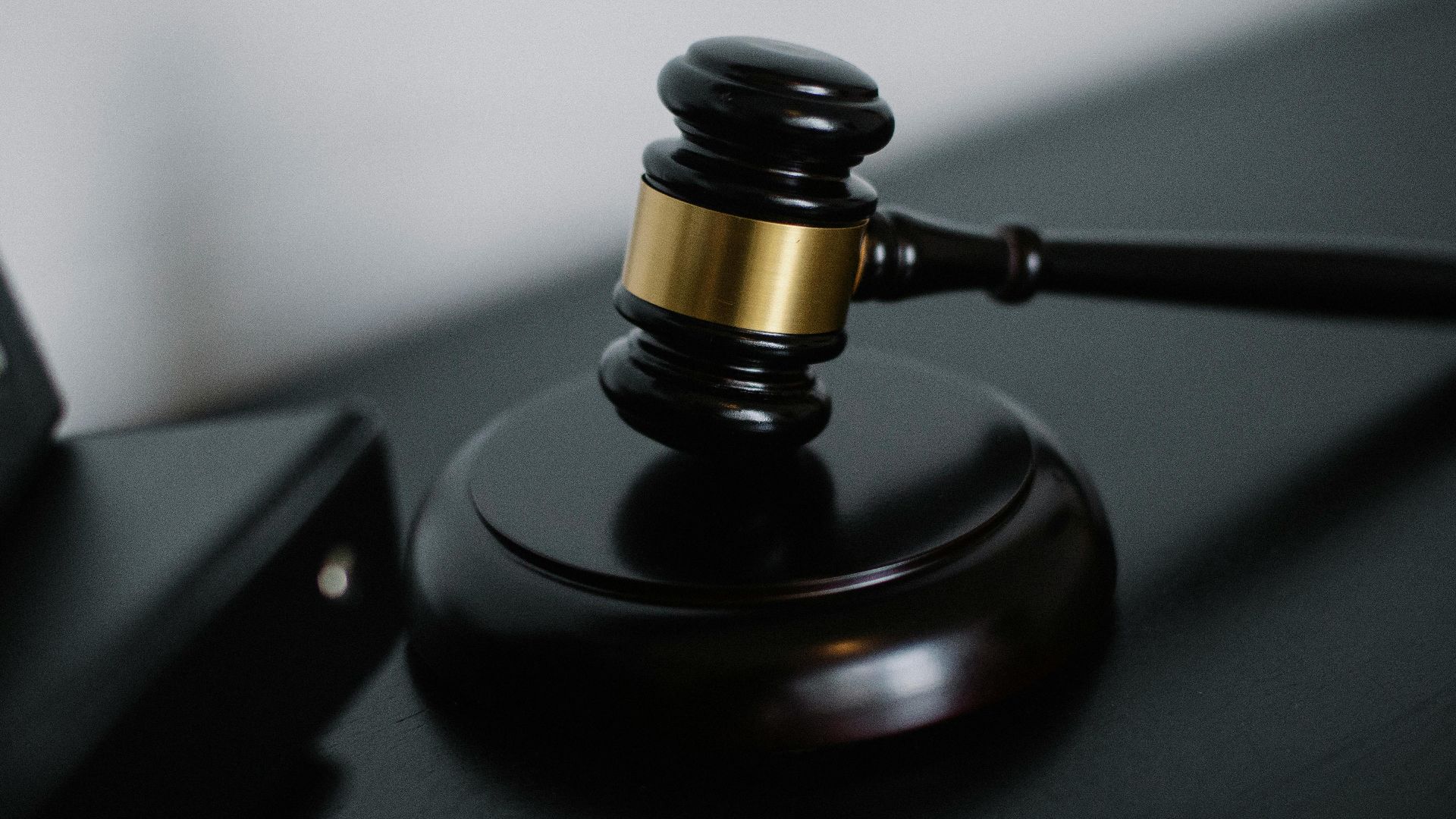 High angle of shiny wooden ceremonial mallet with golden detail placed on judge tale near documents folders