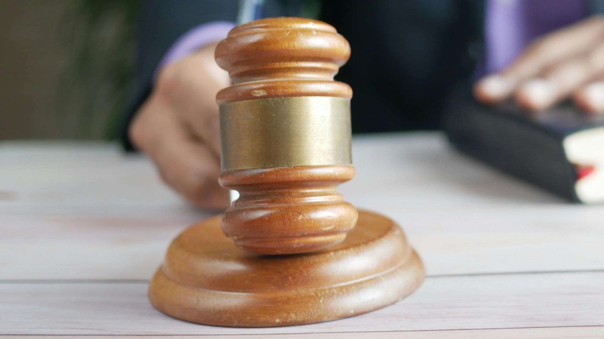 A wooden gavel and legal book represent justice in a court setting, emphasizing order and legal authority.
