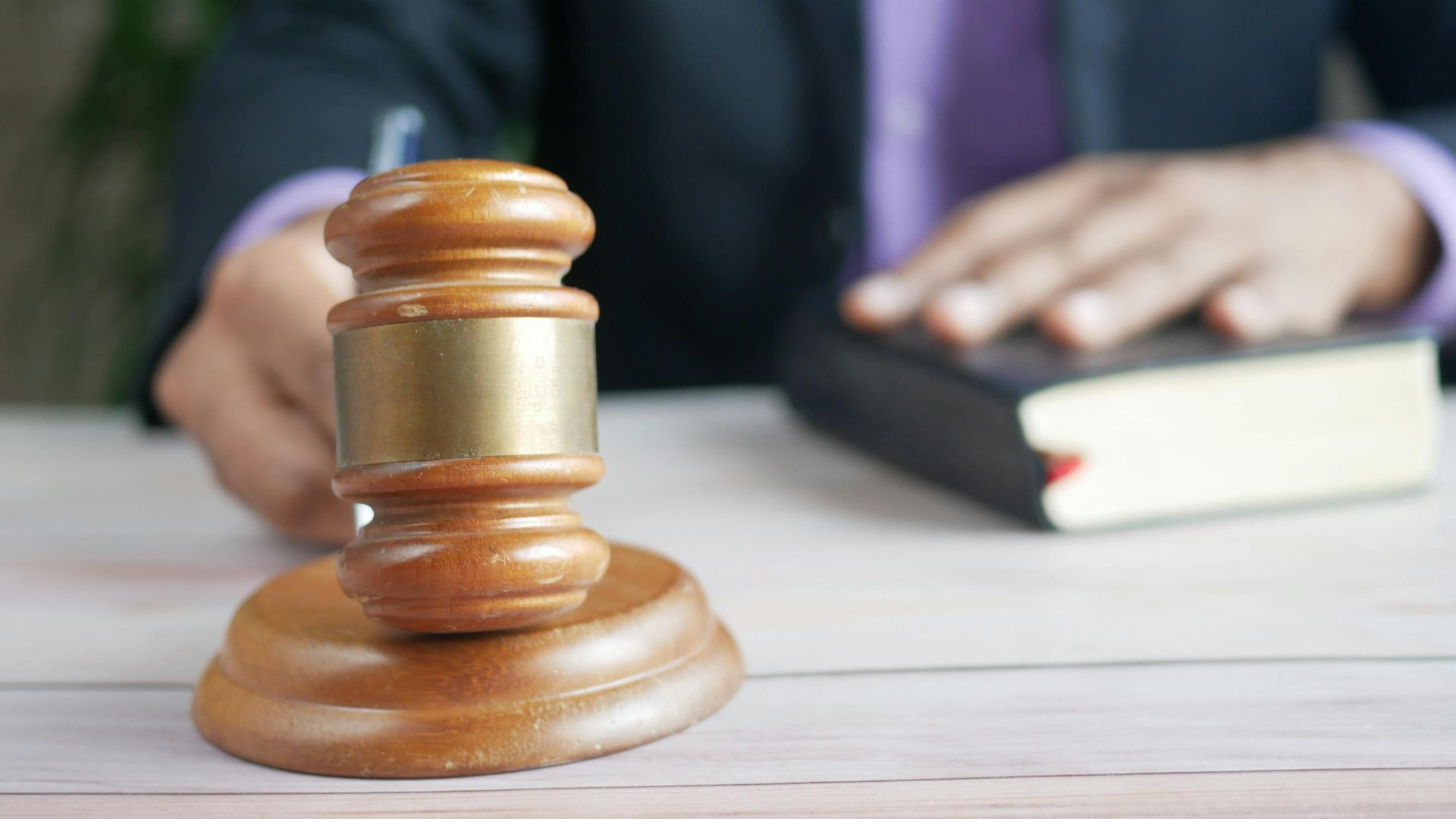 A wooden gavel and legal book represent justice in a court setting, emphasizing order and legal authority.