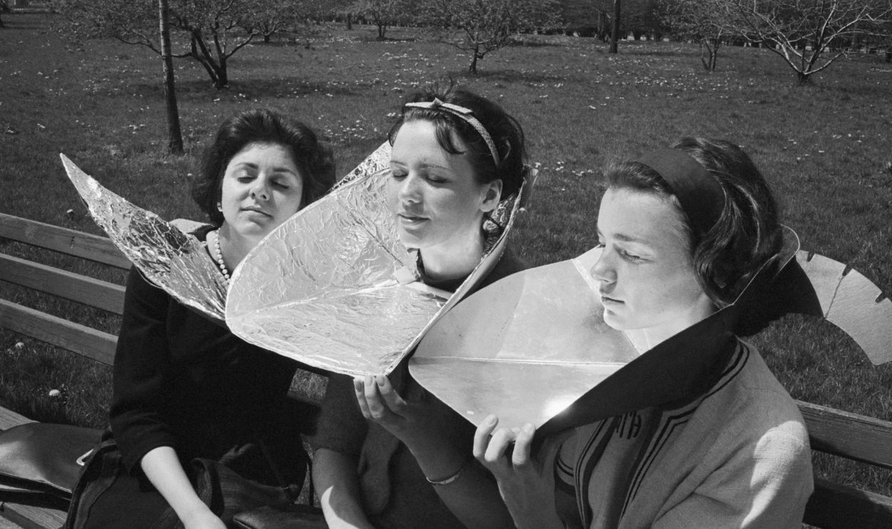 Women Sunbathing In Battery Park (Original Caption) 4/30/1965-New York, NY: (Left to Right) Josephine Virgilio, Brooklyn, and Joan Sharot and Harriette Thaxter of Manhattan, Use home made reflectors for some extra sun as they sit in Battery Park in Manhattan. An 80 degree high for the year was reached.