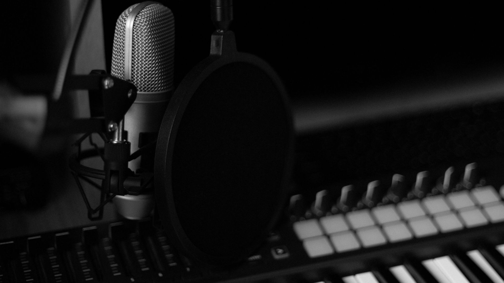 Elegant black and white image of a music studio with a microphone and synthesizer keyboard.