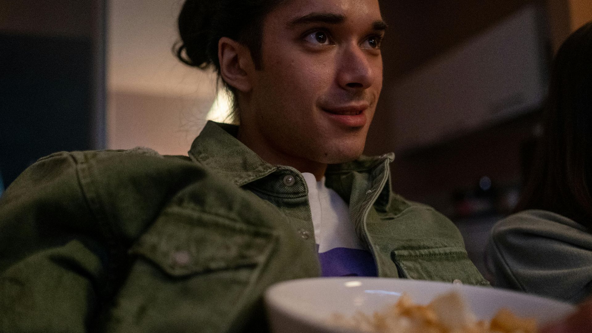 Young man relaxing indoors, watching TV and eating snacks during a cozy movie night.