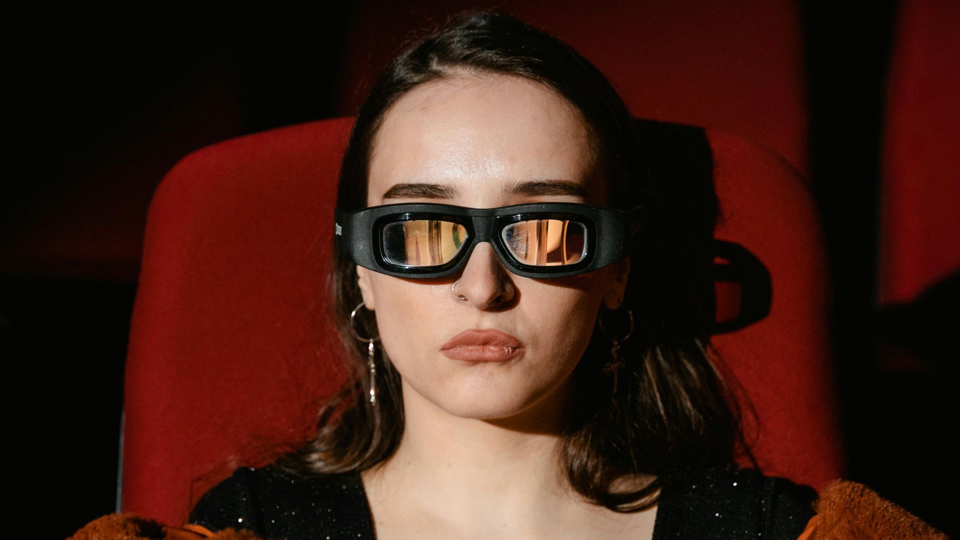 A woman in a fur coat enjoying popcorn while watching a 3D movie in a cinema.