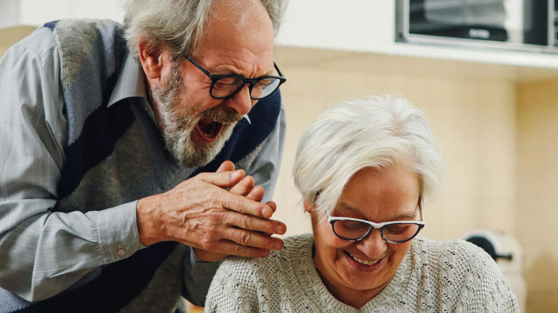 Senior couple enjoying reading a letter at their cozy kitchen table.