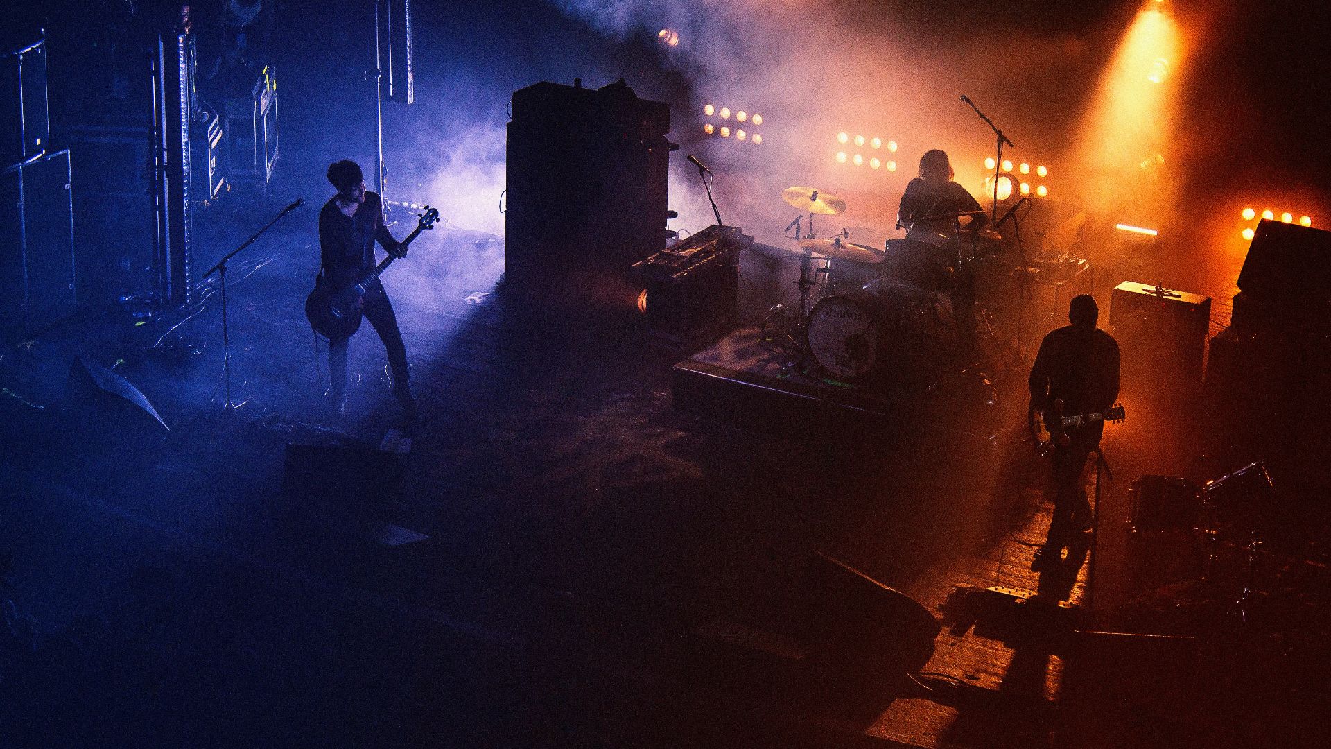 three people playing assorted instruments on stage