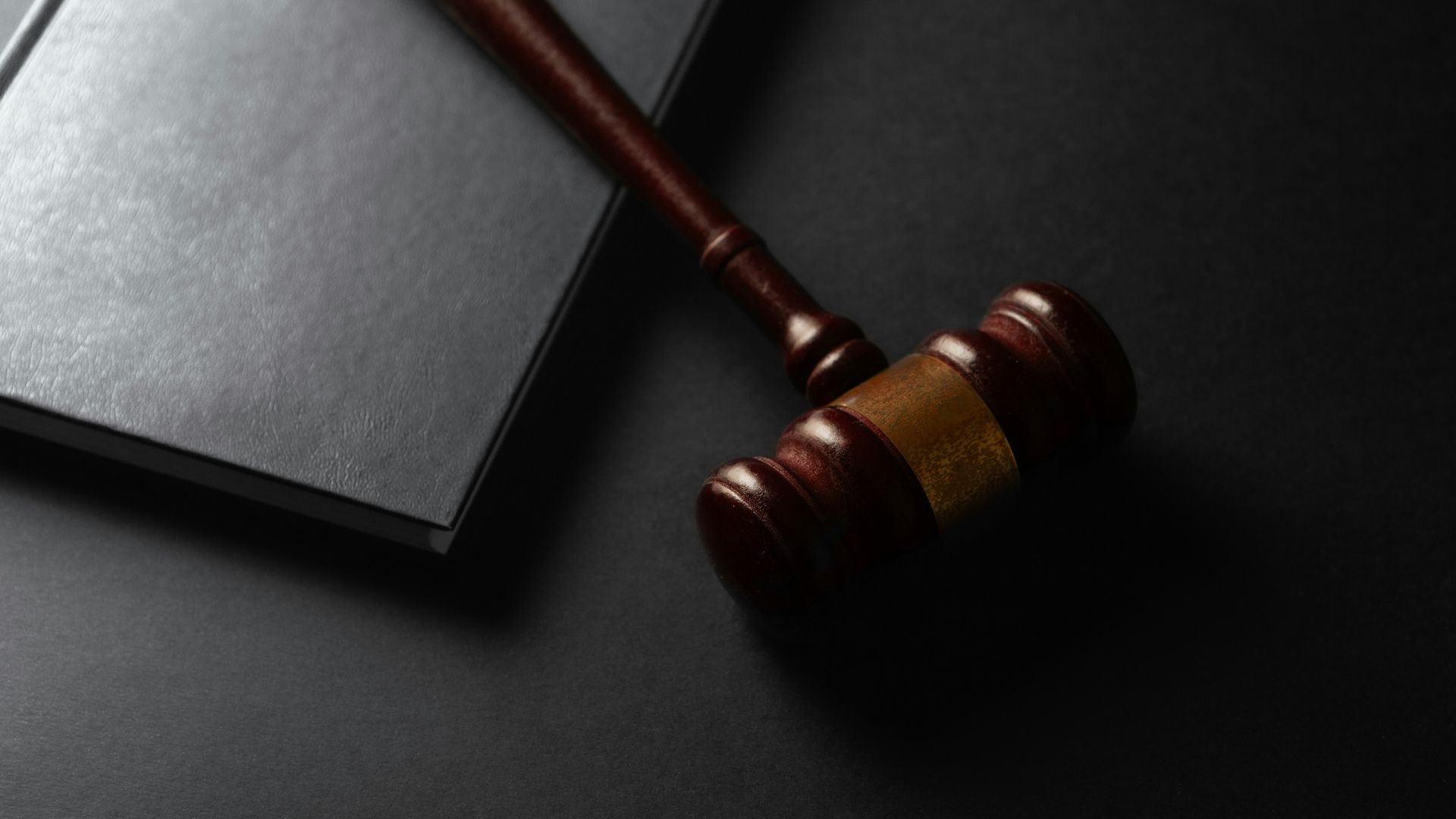 Wooden gavel resting on a dark surface next to book