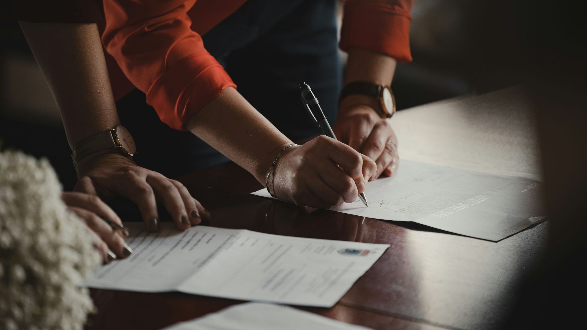 person in orange long sleeve shirt writing on white paper