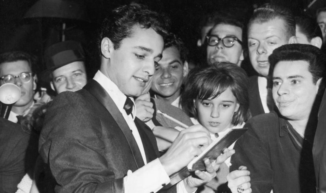 1962: American actor Sal Mineo (1939 - 1976) signs autographs outside the Warner Brothers theater at the premiere of the film, 'The Longest Day,' which was directed by Ken Annakin, Andrew Marton, Gerd Oswald and Bernhard Wicki.