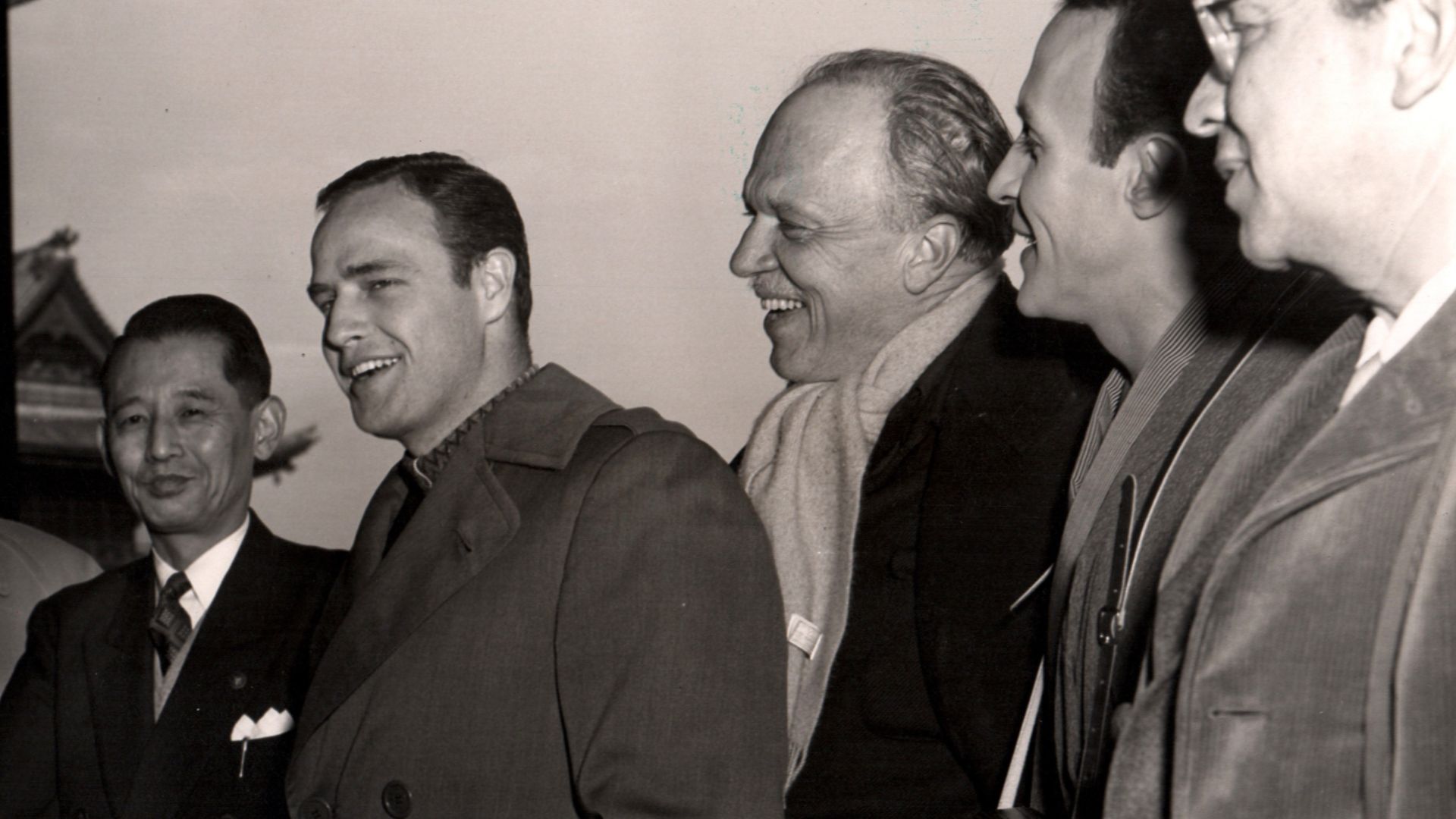 L. to R.: unknown, Marlon Brando, director Joshua Logan, Ricardo Montalban & producer William Goetz, on the set of Sayonara - publicity still (cropped)