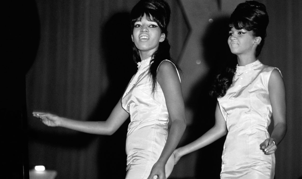 (L-R) American singers Estelle Bennett (1941 - 2009) and Nedra Talley, of the American girl group The Ronettes, sing on stage during Murray the K Holiday Show at the Brooklyn Fox Theatre in New York, New York, September 4, 1963.