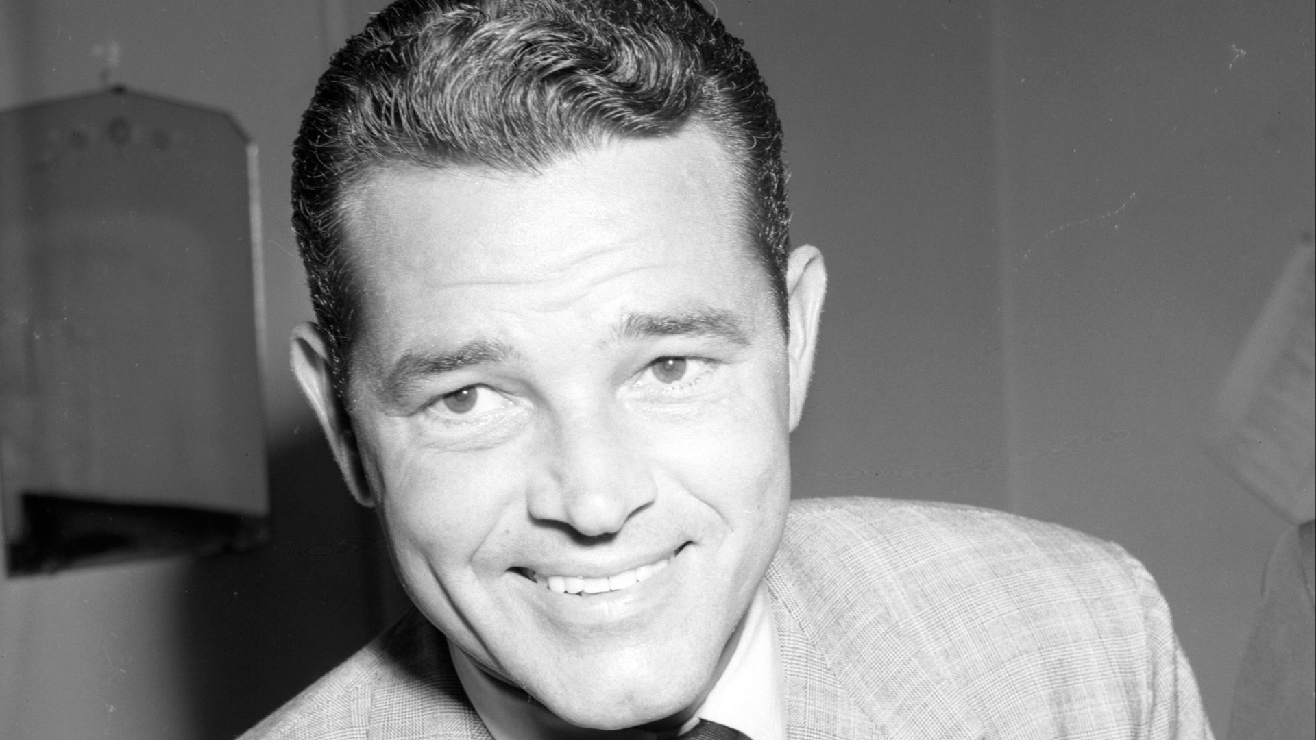 Tom Neal smiles to the camera in Los Angeles District Attorney S. Ernest Roll's office during questioning regarding his fight with Franchot Tone.
