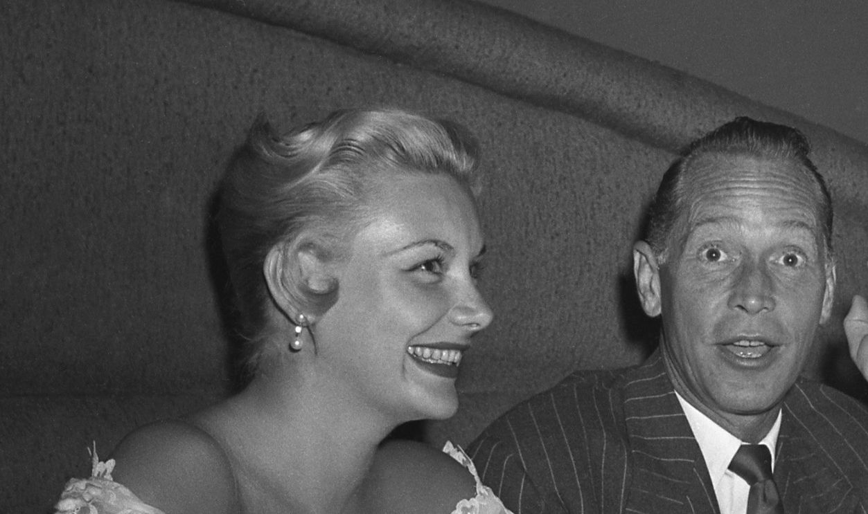 Actress Barbara Payton and fiancee actor Franchot Tone are greeted by the Maitre D' of the Mocambo nightclub on July 8, 1951 in Los Angeles, California.