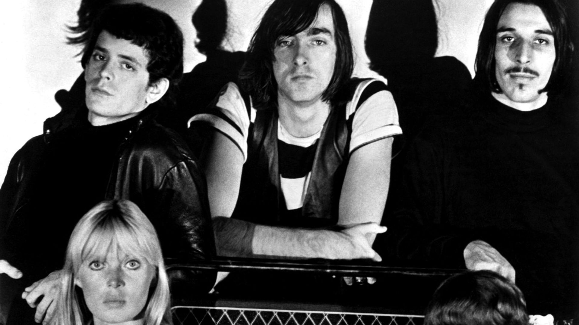 A publicity photo of the American rock band The Velvet Underground circa 1966, around the time that they were recording their debut album The Velvet Underground & Nico. The band members are positioned around a Vox-brand amplifier. Clockwise from top left: