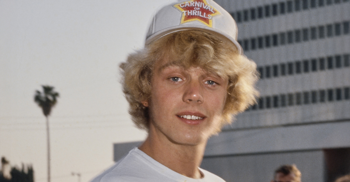 American actor and singer John Schneider, wearing a white t-shirt and a 'Carnival of Thrills' baseball cap, United States, circa 1980. 'Carnival of Thrills' is the title of an episode in the CBS action-adventure drama 'The Dukes of Hazzard'. 