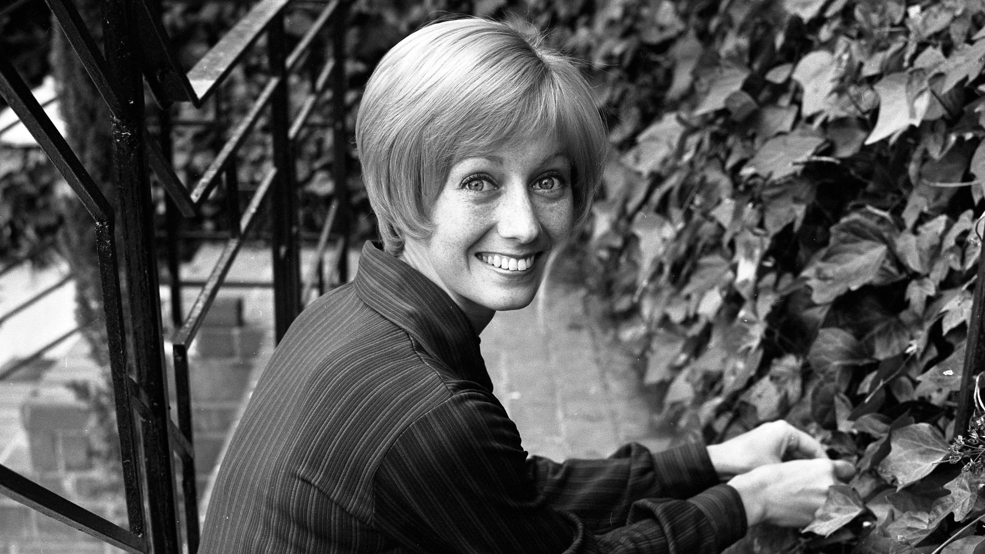 Actress Sandy Duncan seated on ivy covered steps