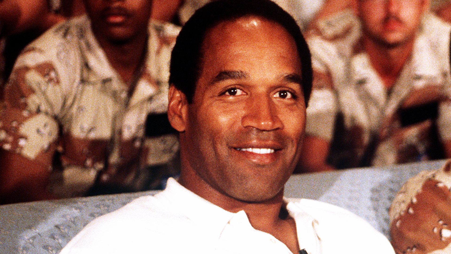 NBC Sports commentator and former professional football player O. J. Simpson sits with a group of servicemen to watch a Thanksgiving Day football game. Simpson is visiting U.S. troops who are in the region for Operation Desert Shield.