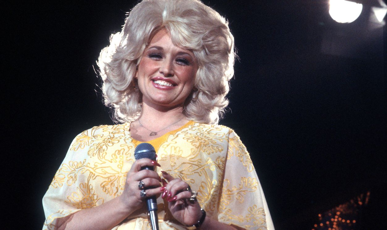  Country singer Dolly Parton performs onstage wearing a yellow dress, circa 1975, Los Angeles, California. 