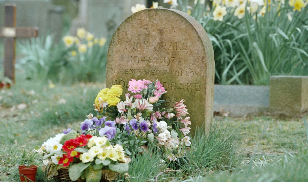 Getty Images - 2155382038 - The grave of acoustic singer and songwriter Nick Drake, his ashes under an oak tree in the graveyard of the Church of St Mary Magdalene, Tanworth-in-Arden, Warwickshire, England with fresh flowers and letters and poems.