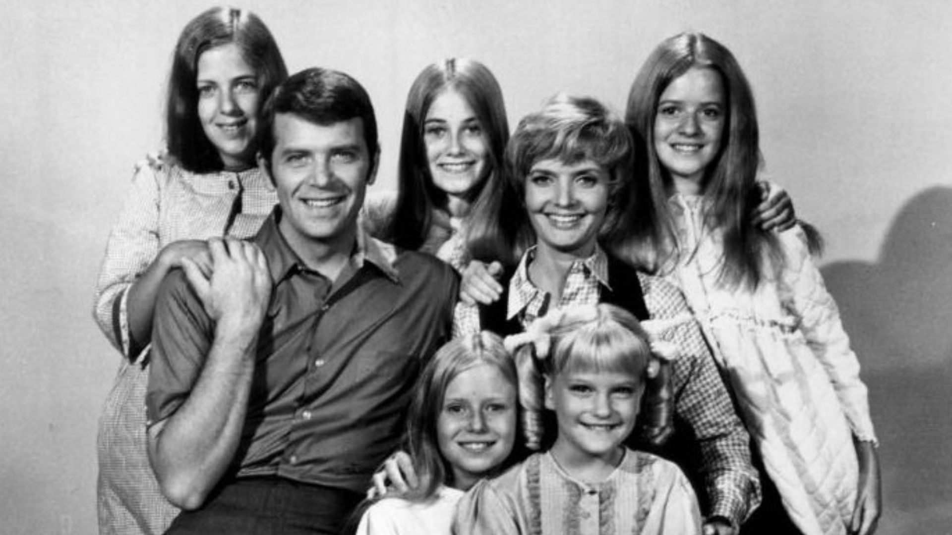 Publicity photo of American actors, (front row; sitting; L–R) Eve Plumb, Susan Olsen, (second row; sitting; L–R) Robert Reed, Florence Henderson, (back row; standing; L-R) Carolyn Reed, Maureen McCormick and Barbara Henderson Bernstein promoting the Octob