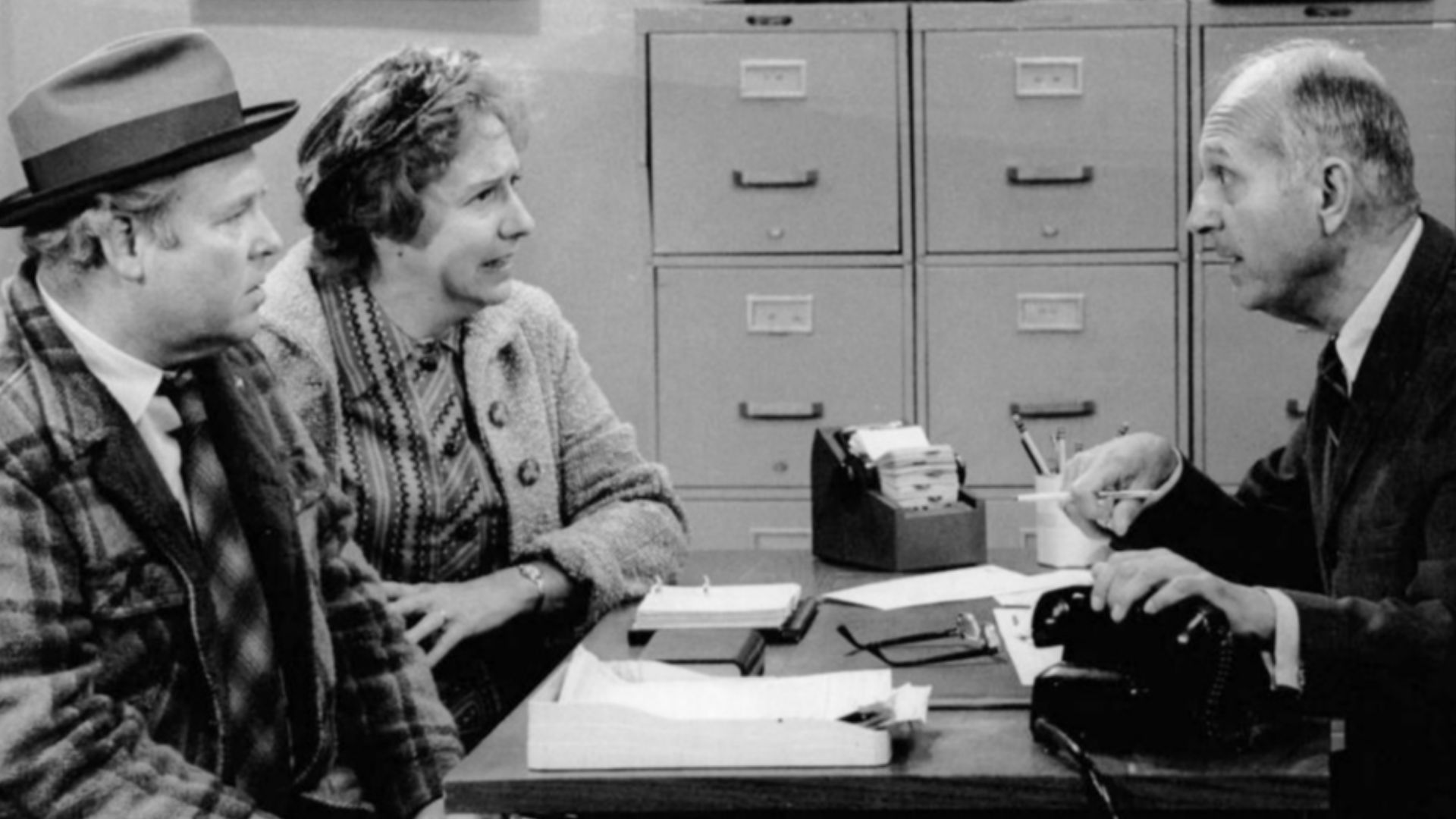 Publicity photo of Carroll O'Connor and Jean Stapleton as Archie and Edith Bunker and guest star James O'Reare as the government official.  In this 27 October 1973 episode, the Bunkers try to convince the government that its computers are wrong; Archie is