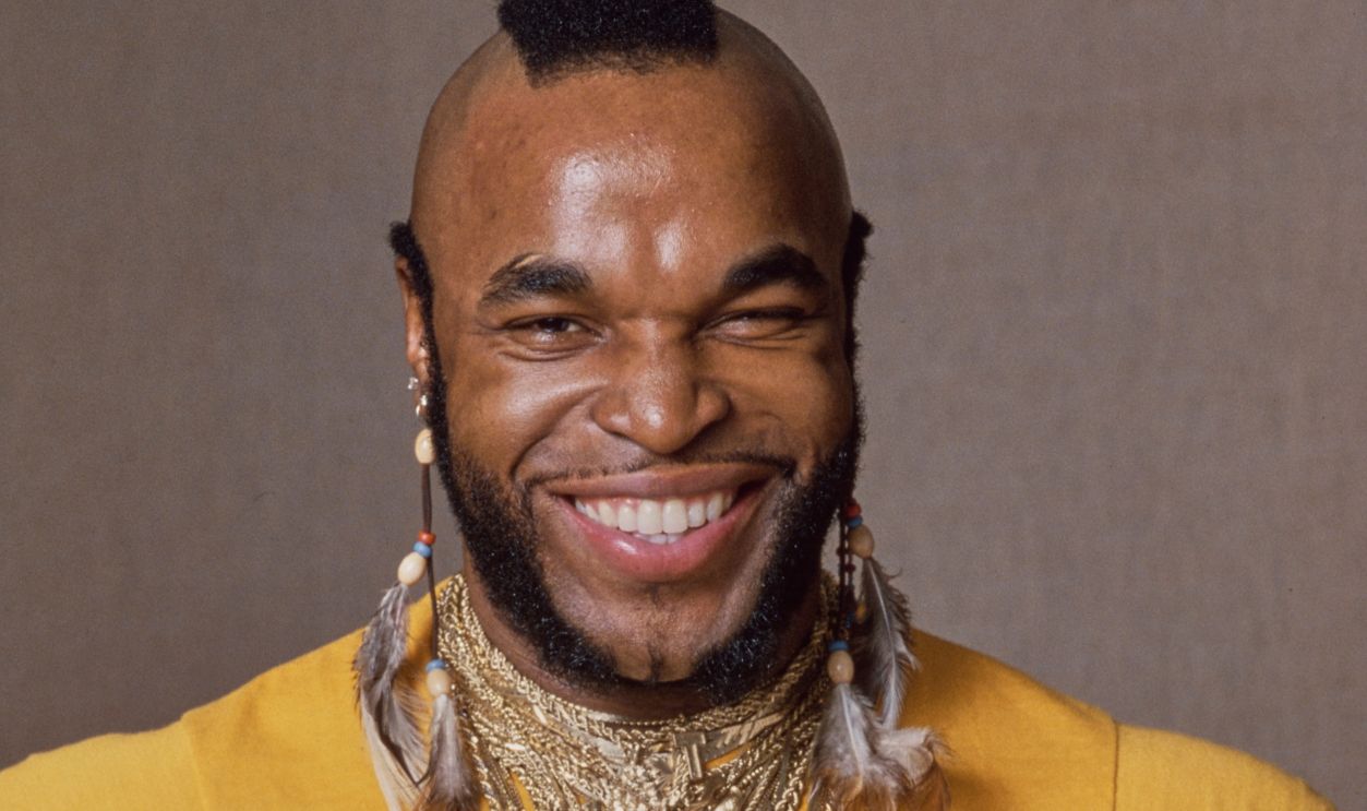 Mr. T, American Actor American actor Mr T, wearing a yellow t-shirt (with 'Rocky, The Italian Stallion' printed on the chest), with necklaces and feather earrings, during a studio portrait session, United States, circa 1982. Mr T appeared as Clubber Lang in 'Rocky III', released in 1982. 