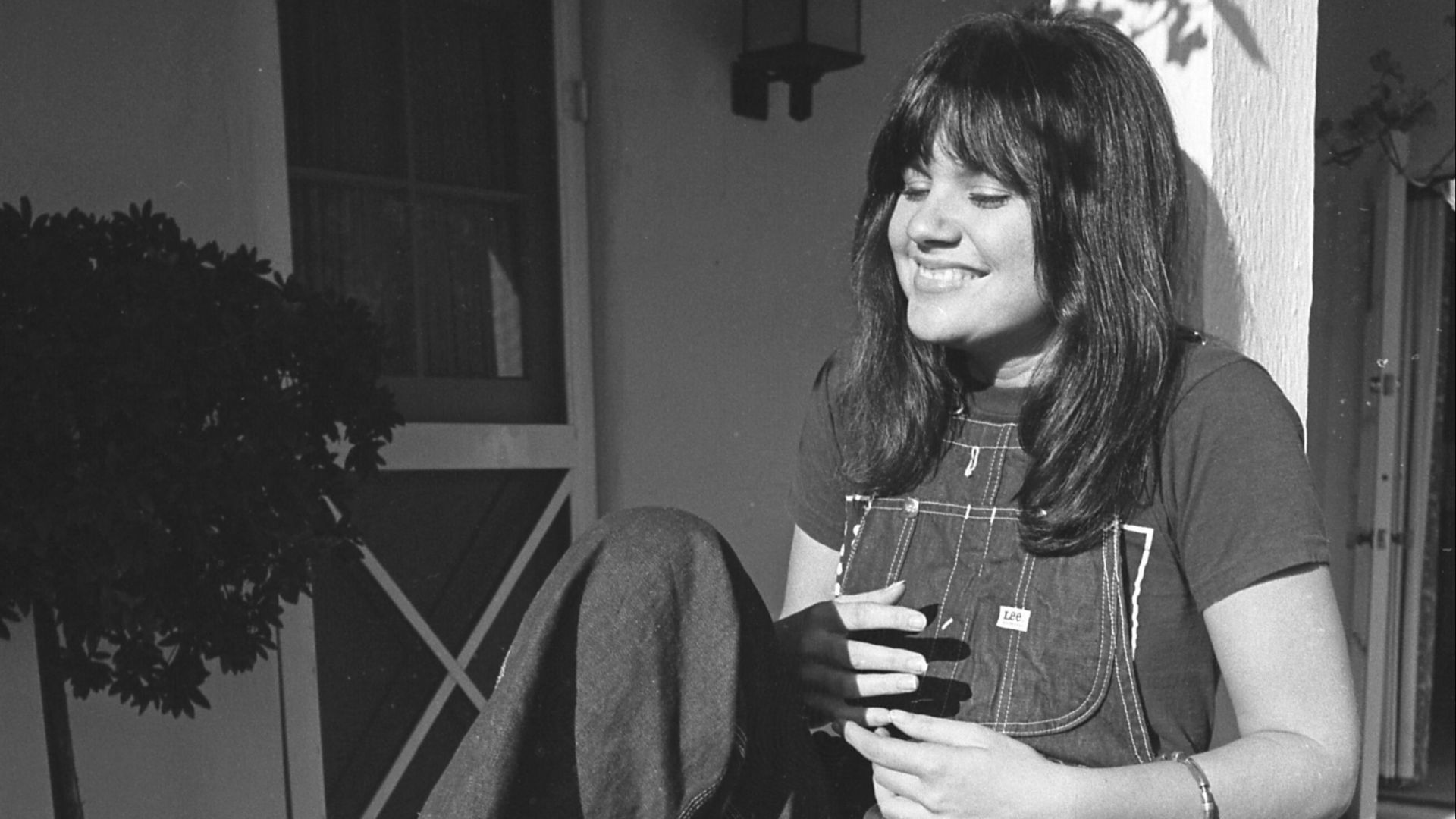 Linda Ronstadt reclining on porch railing in Los Angeles, California
