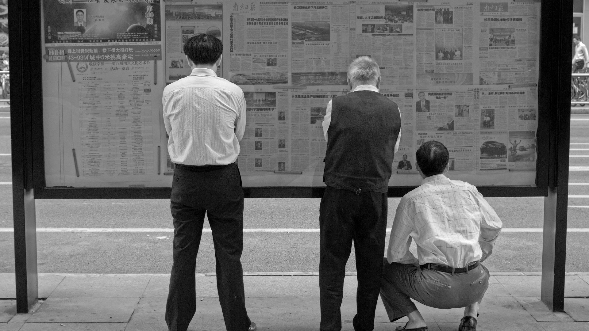 Some men are reading public newspapers in the streets, Nanjing, China.