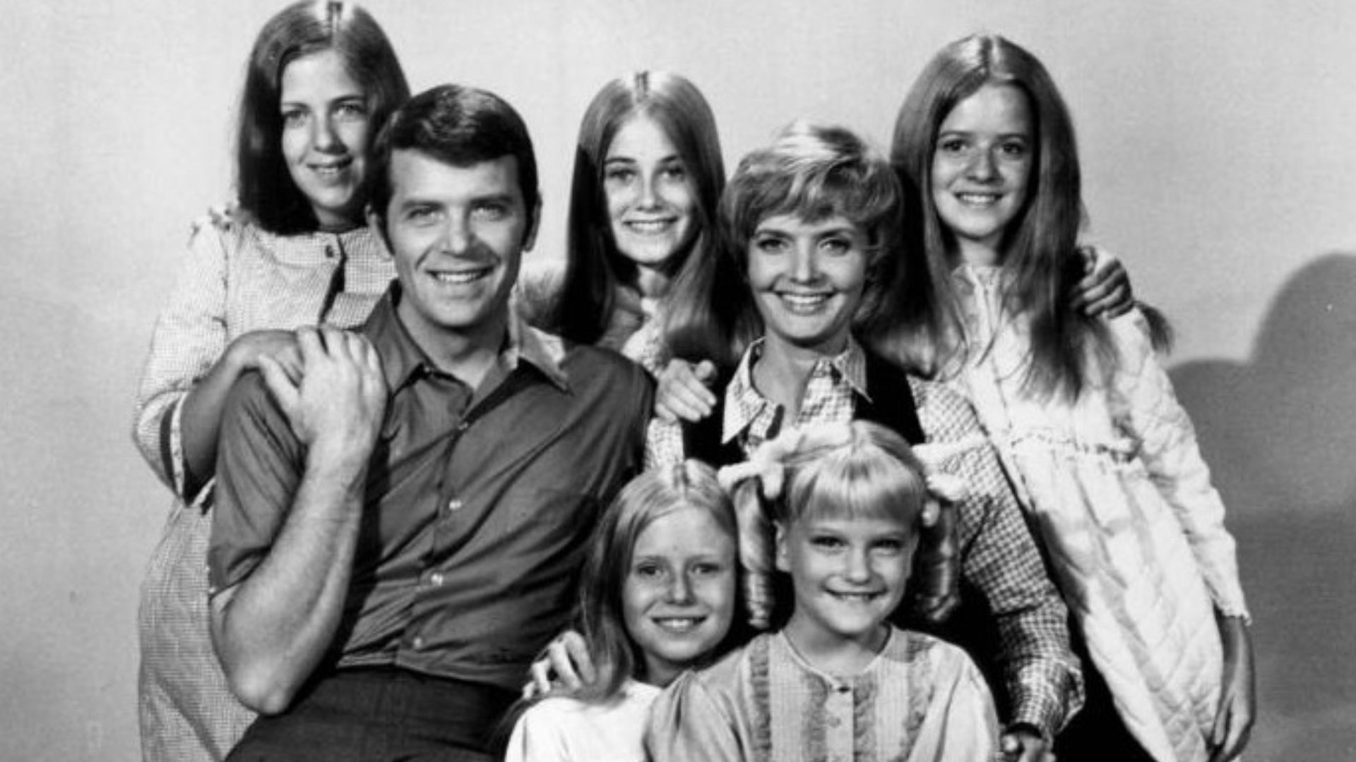 Publicity photo of American actors, (front row; sitting; L–R) Eve Plumb, Susan Olsen, (second row; sitting; L–R) Robert Reed, Florence Henderson, (back row; standing; L-R) Carolyn Reed, Maureen McCormick and Barbara Henderson Bernstein promoting the Octob
