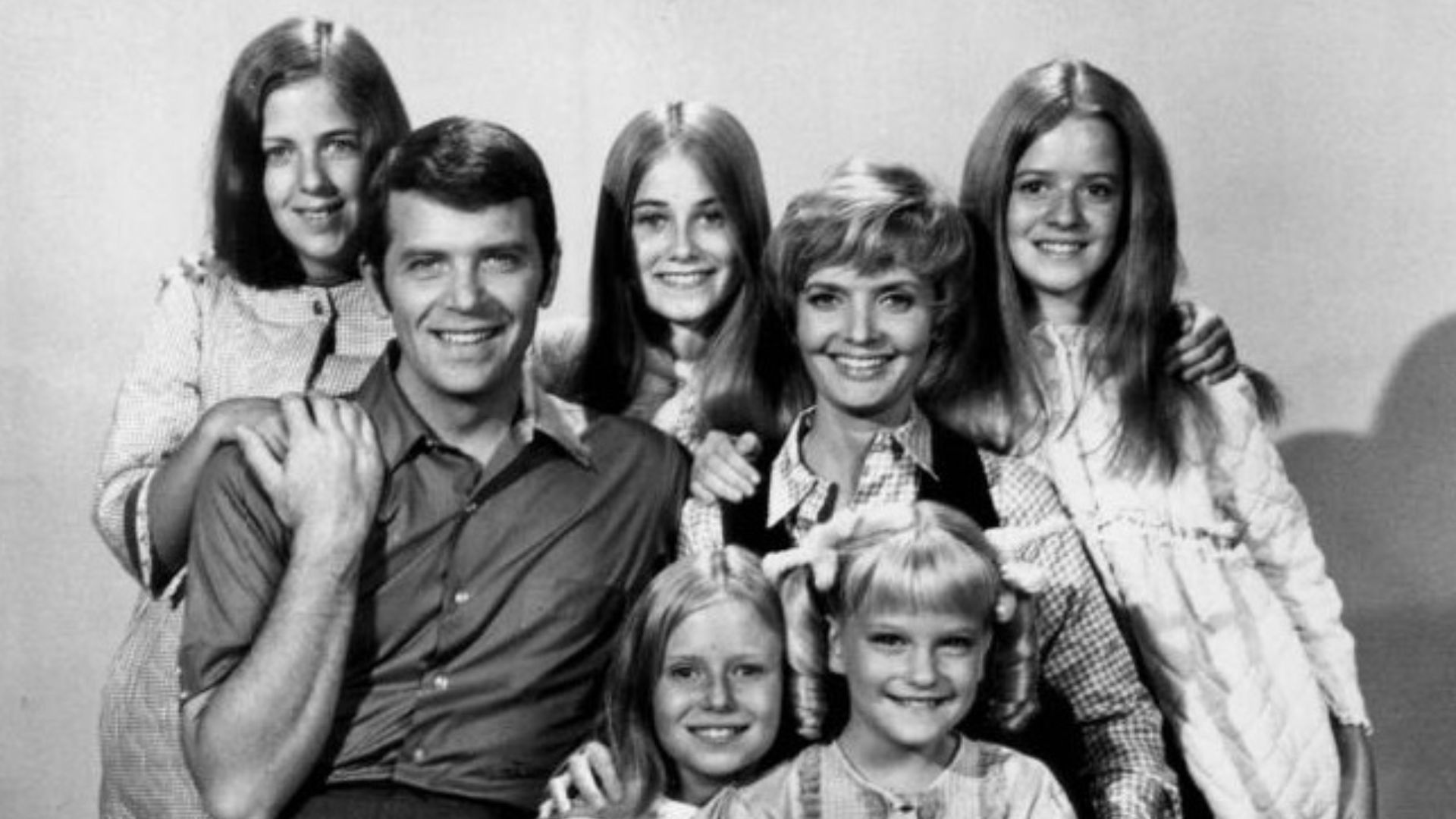 Publicity photo of American actors, (front row; sitting; L–R) Eve Plumb, Susan Olsen, (second row; sitting; L–R) Robert Reed, Florence Henderson, (back row; standing; L-R) Carolyn Reed, Maureen McCormick and Barbara Henderson Bernstein promoting the Octob