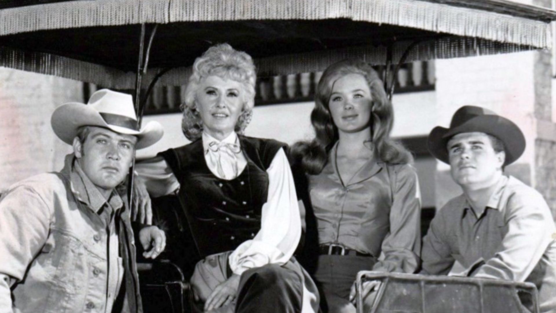 Cast photo from the television program The Big Valley.  From left: Lee Majors (Heath Barkley), Barbara Stanwyck (Victoria Barkley), Linda Evans (Audra Barkley), Charles Briles (Eugene Barkley).  Briles' character appeared only a few times in the first sea