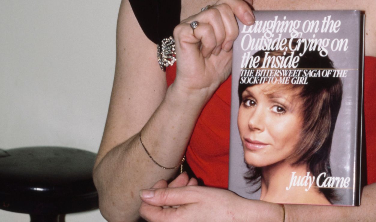 Judy Carmen holds up a copy of her new book 