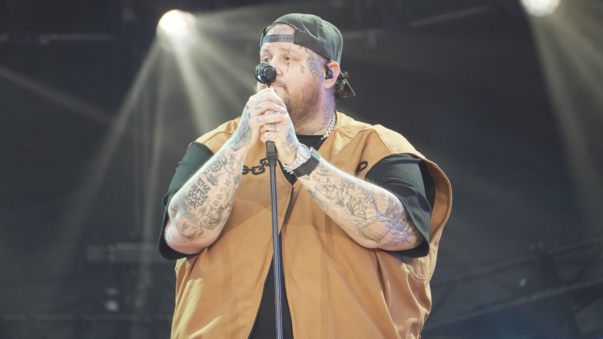 Jellyroll performing live at the Global Citizen Festival on September 28, 2024. The artist is on stage ready to sing, holding both arms with microphones, engaging the audience with his energetic performance.