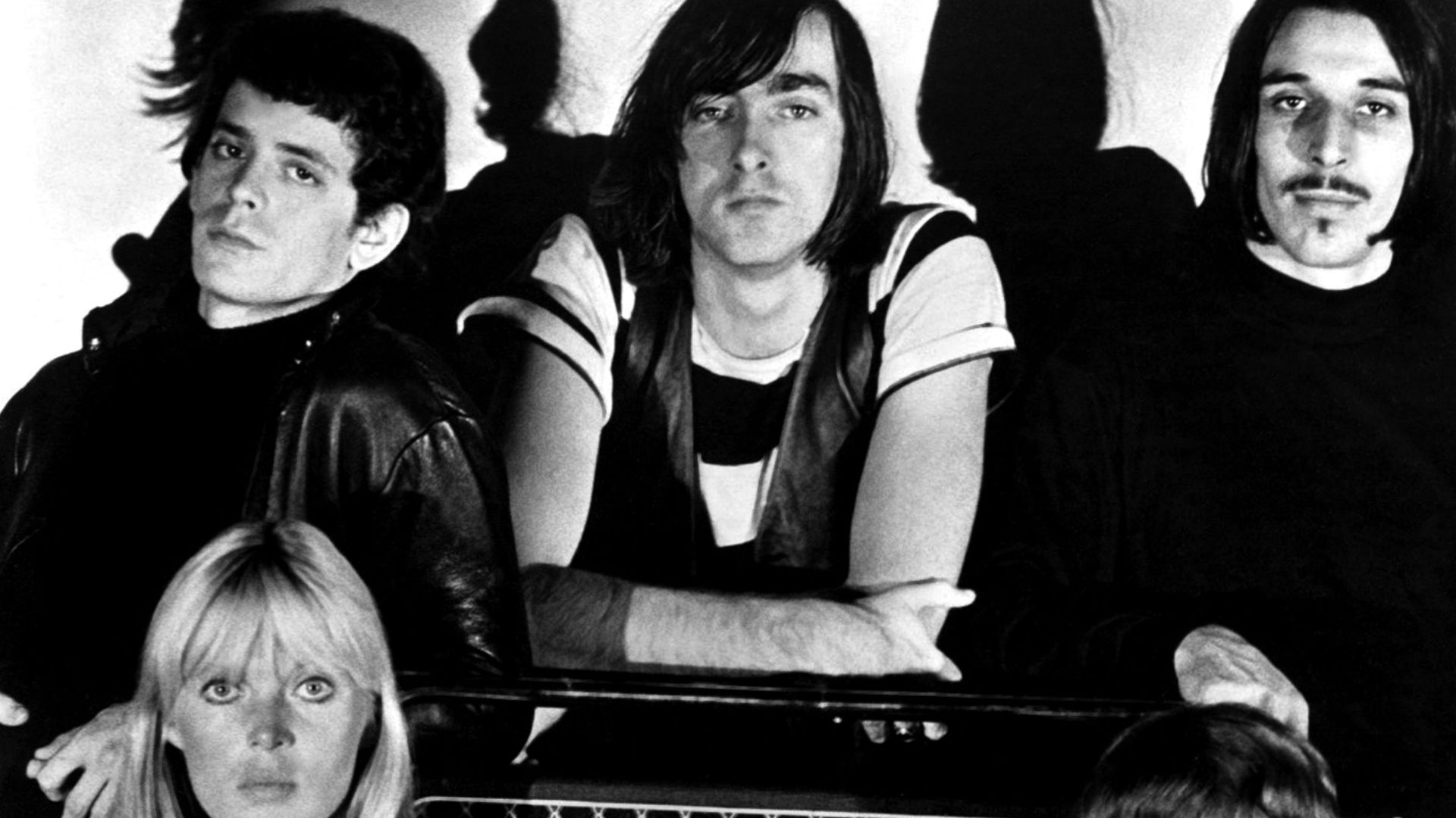 A publicity photo of the American rock band The Velvet Underground circa 1966, around the time that they were recording their debut album The Velvet Underground & Nico. The band members are positioned around a Vox-brand amplifier. Clockwise from top left: