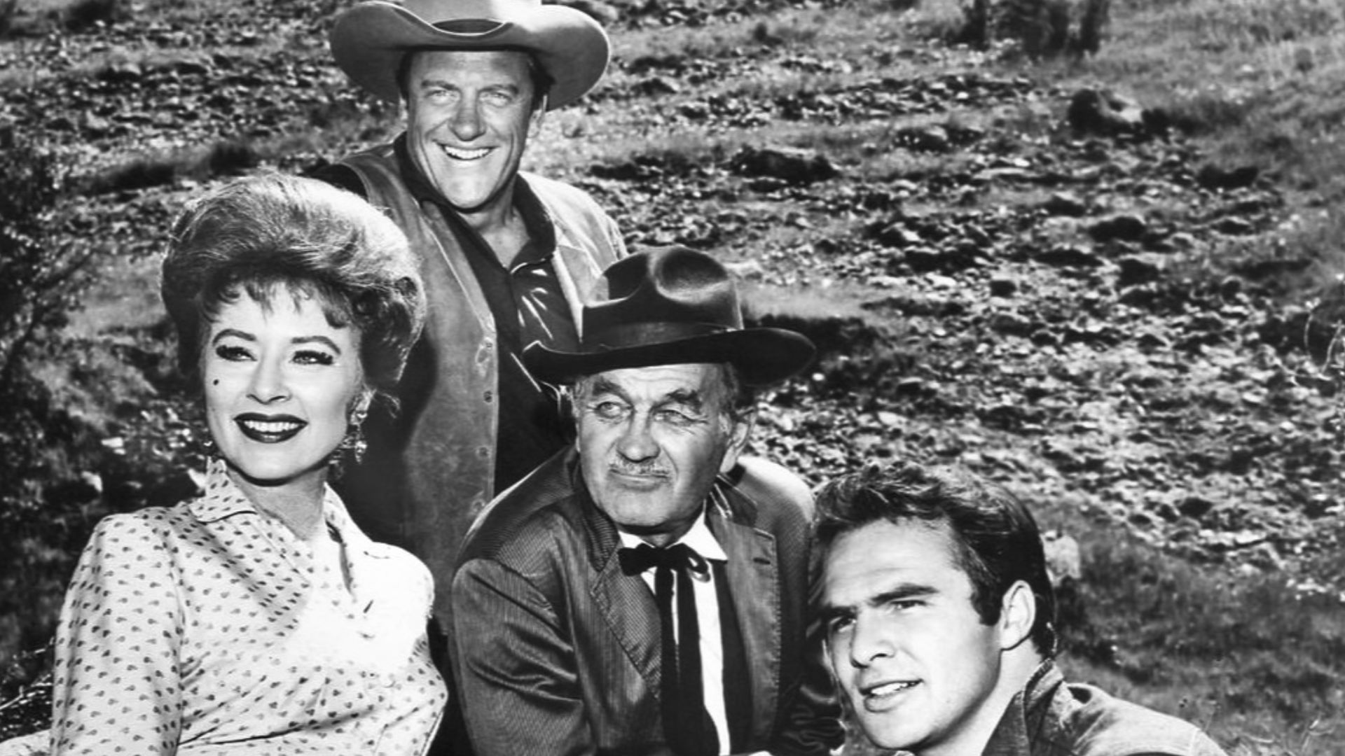 Photo of the main cast for the television program Gunsmoke in 1963.  From left: Amanda Blake (Miss Kitty), James Arness (Matt Dillon), Milburn Stone (Doc Adams), and Burt Reynolds (Quint Asper).