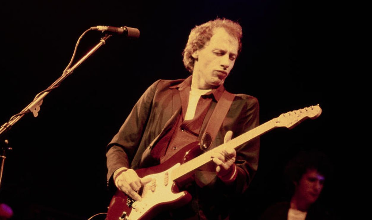 British guitarist, singer and songwriter Mark Knopfler plays a Schecter Stratocaster as his band, British rock band Dire Straits, performs live in concert, circa 1985.