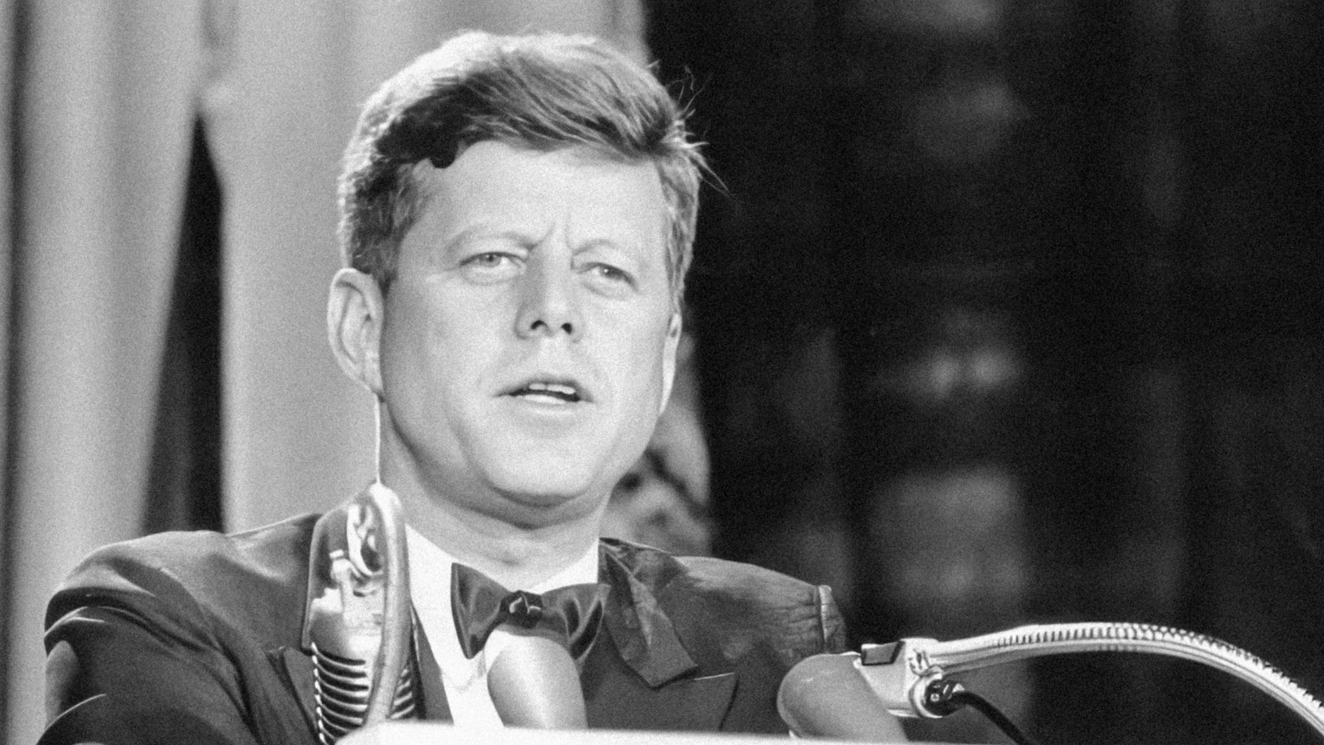 a man in a suit and tie standing at a podium
